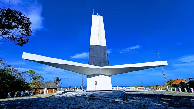 Farol do Cabo Branco, torre branca e preta com três abas na base que lembram uma planta de sisal, sob céu azul intenso
