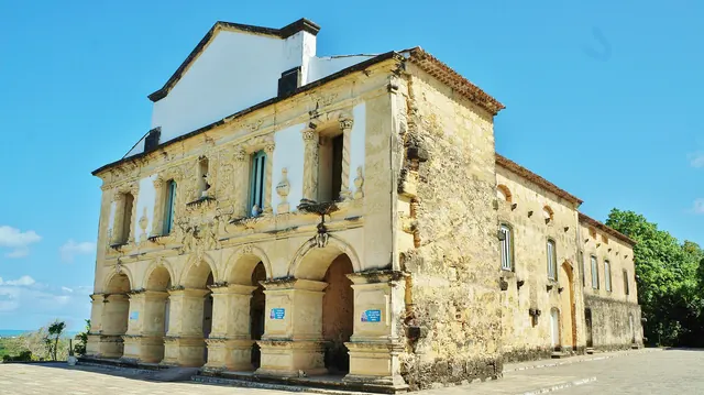 Igreja de Nossa Senhora da Guia, em Lucena, com fachada de pedra e arcadas no térreo