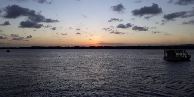 Anoitecer no rio Paraíba na Praia do Jacaré, com uma embarcação parada na água